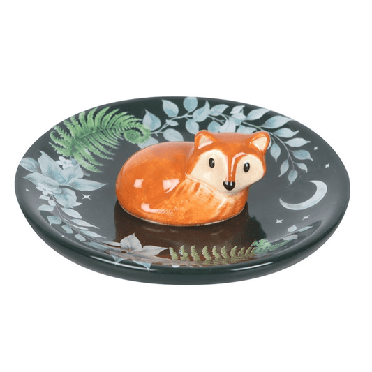 Decorative plate with a fox design on a black background with green and blue leaf patterns