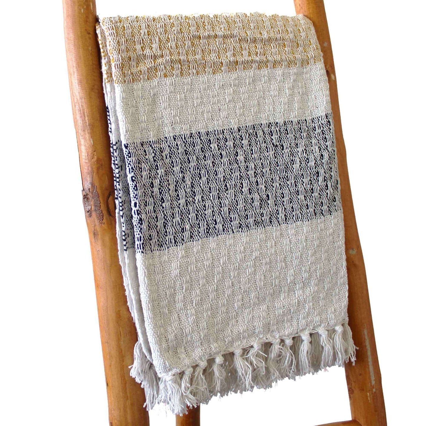 Boho Comfort Throws - Mellow Mattala throw displayed on a wooden ladder, featuring cream tones, grey stripes, and tasselled edges.