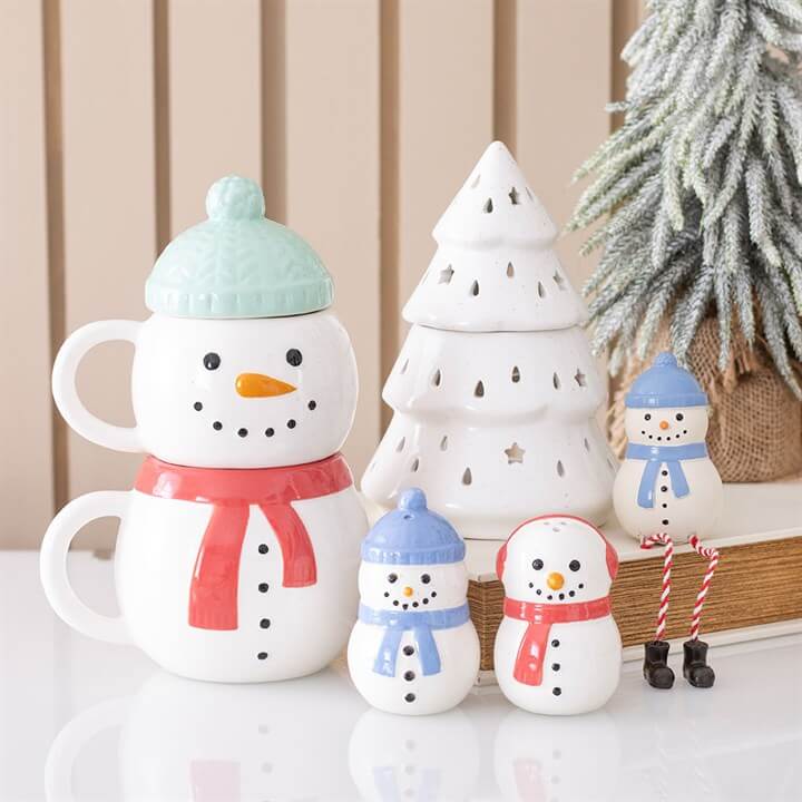 White Winter Fir Tree Oil Burner next to cheerful snowman mugs and festive decorations for holiday displays.