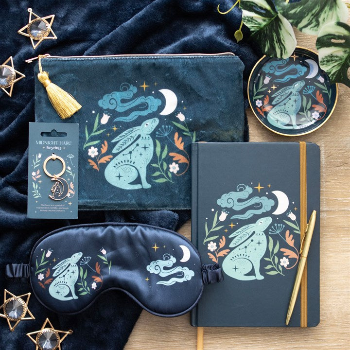 Set of decorative items including a pouch, notebook, eye mask, and keychain with rabbit illustrations on a wooden surface.