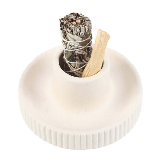 White ceramic holder with a sage bundle and wooden stick on a white background