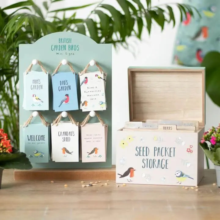 Decorative seed packet display with wooden storage box on a wooden surface.