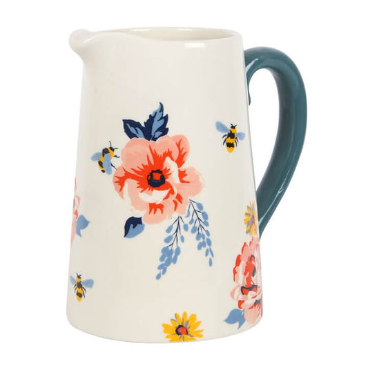 Ceramic pitcher with floral design and blue handle on a white background