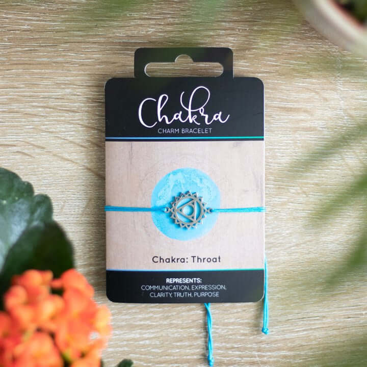 Throat Chakra Charm Bracelet packaging featuring blue string, metal charm, and descriptions of clarity and expression.
