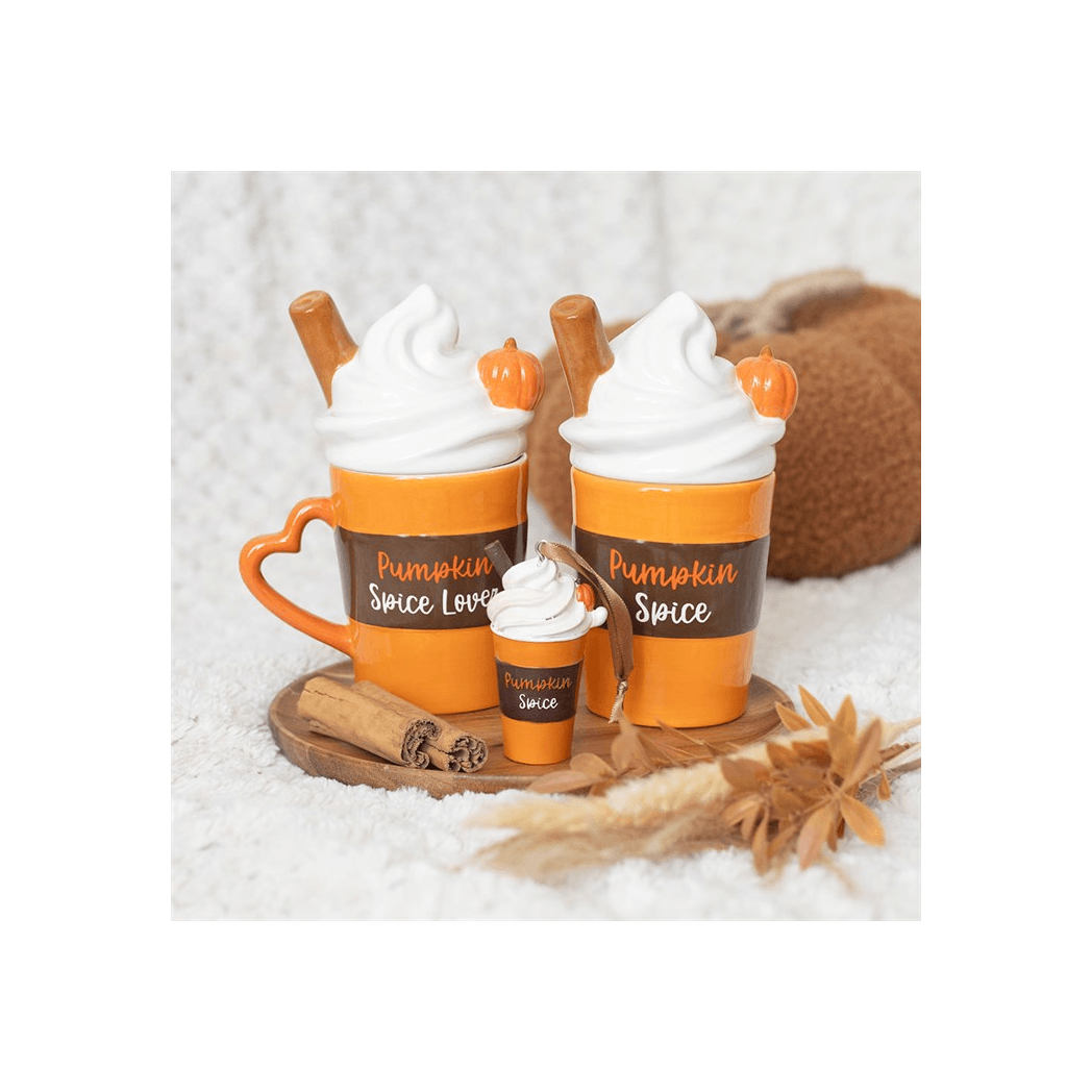 Hanging Ornament shaped like a pumpkin spice latte next to decorative cinnamon sticks and autumn leaves.