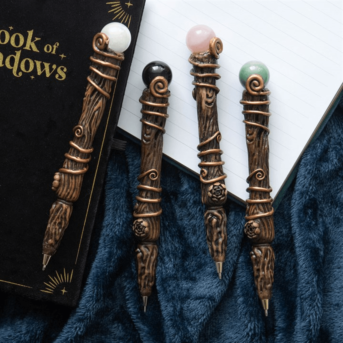 Four ornate sticks with gemstones on a blue fabric background