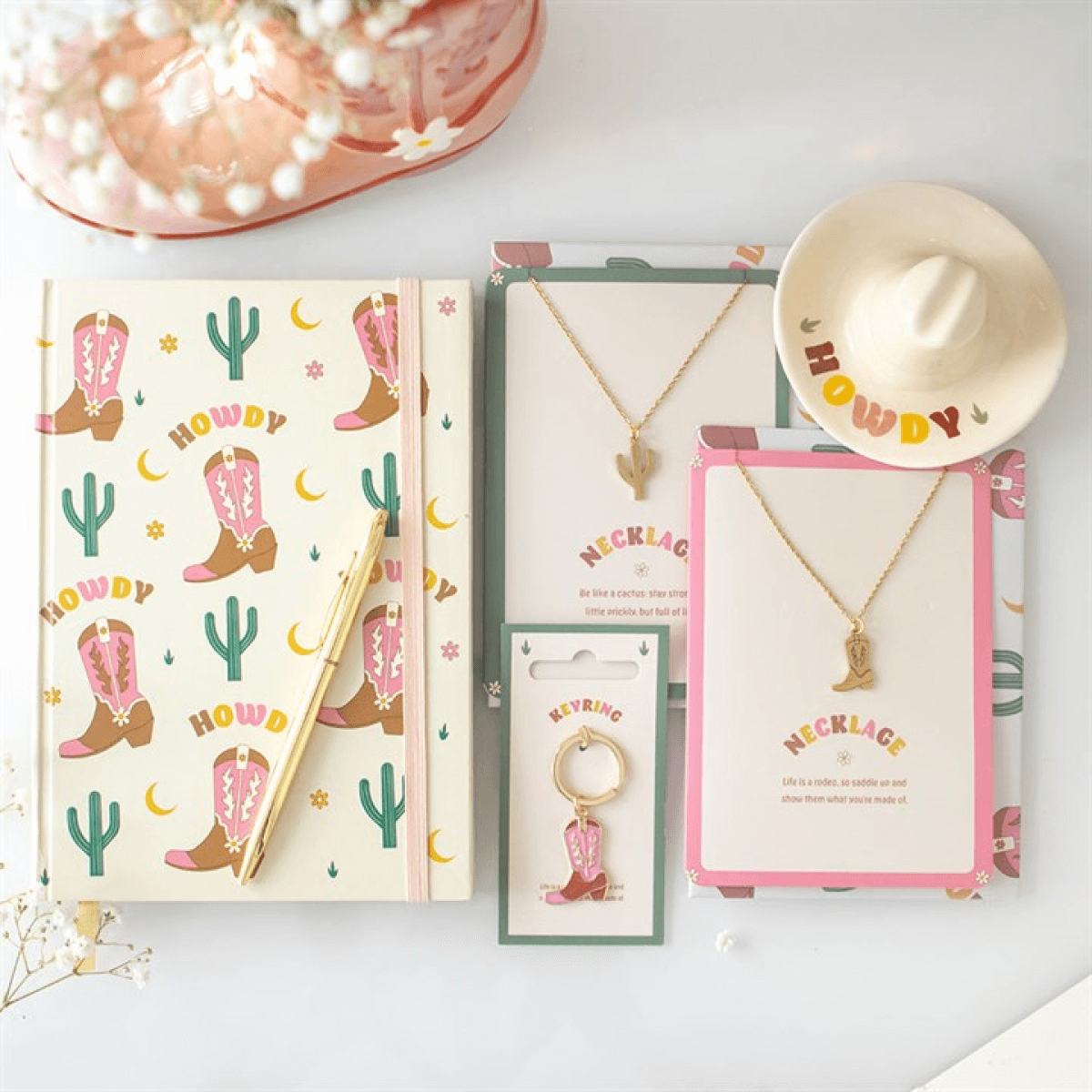 Cowboy-themed stationery set with notebook, pen, necklaces, and keychain on a white surface.