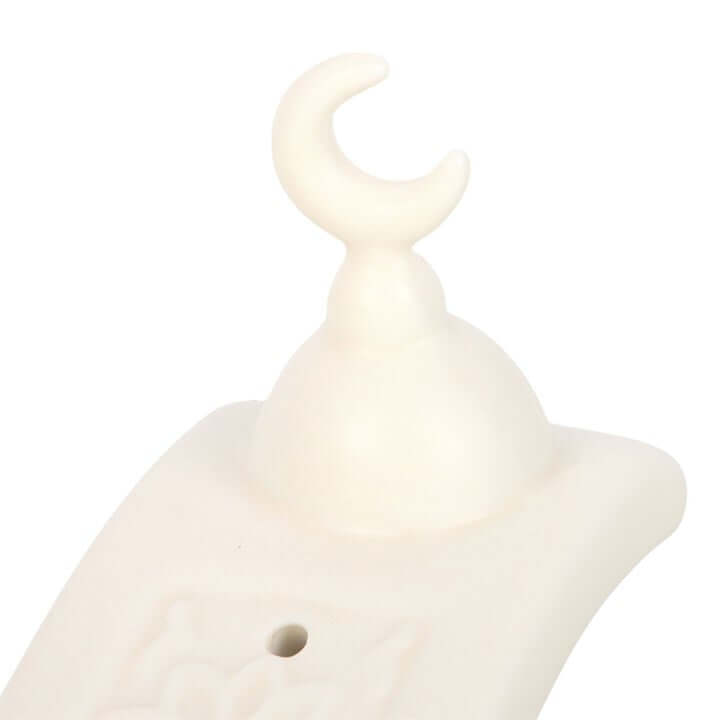 White ceramic sculpture of a crescent moon on a white background