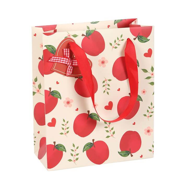 Gift bag with red apple pattern and ribbon on a white background