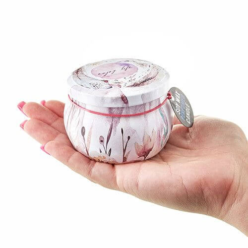 Art Tin Candle in a hand featuring floral design and colorful packaging.