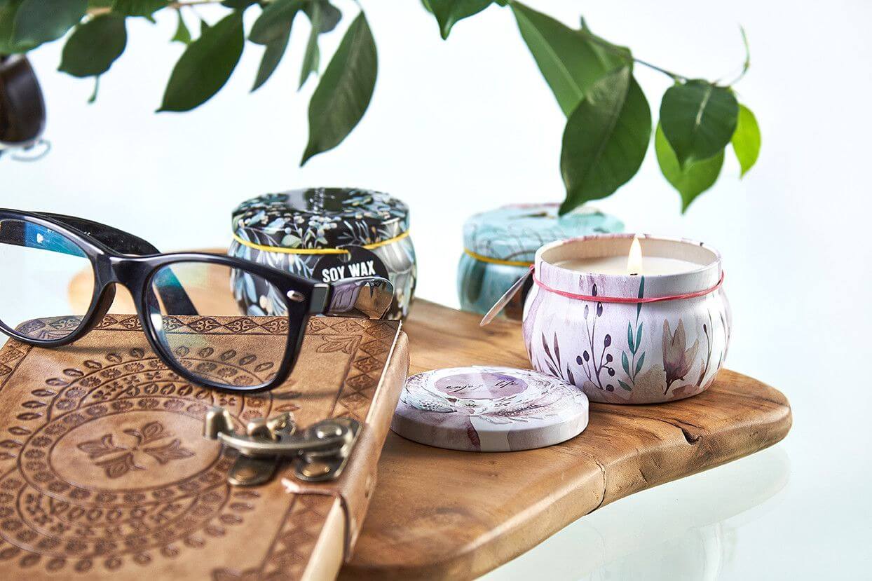 Art Tin Candle assortment featuring Russian Dolls design, natural soy wax, and stylish glasses on a wooden table.