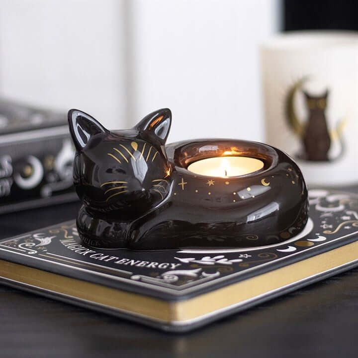 Black Cat Magick Curled Cat Tealight Holder on a book surface, featuring a tealight candle inside.