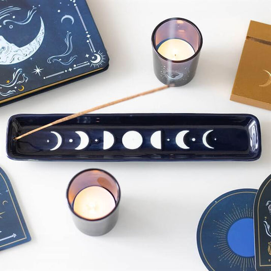 Blue Moon Phase Ceramic Incense Ash Catcher with candles and celestial artwork around it.