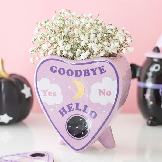 Pastel flower vase shaped like a planchette with text, featuring fresh blooms for mystical decor.