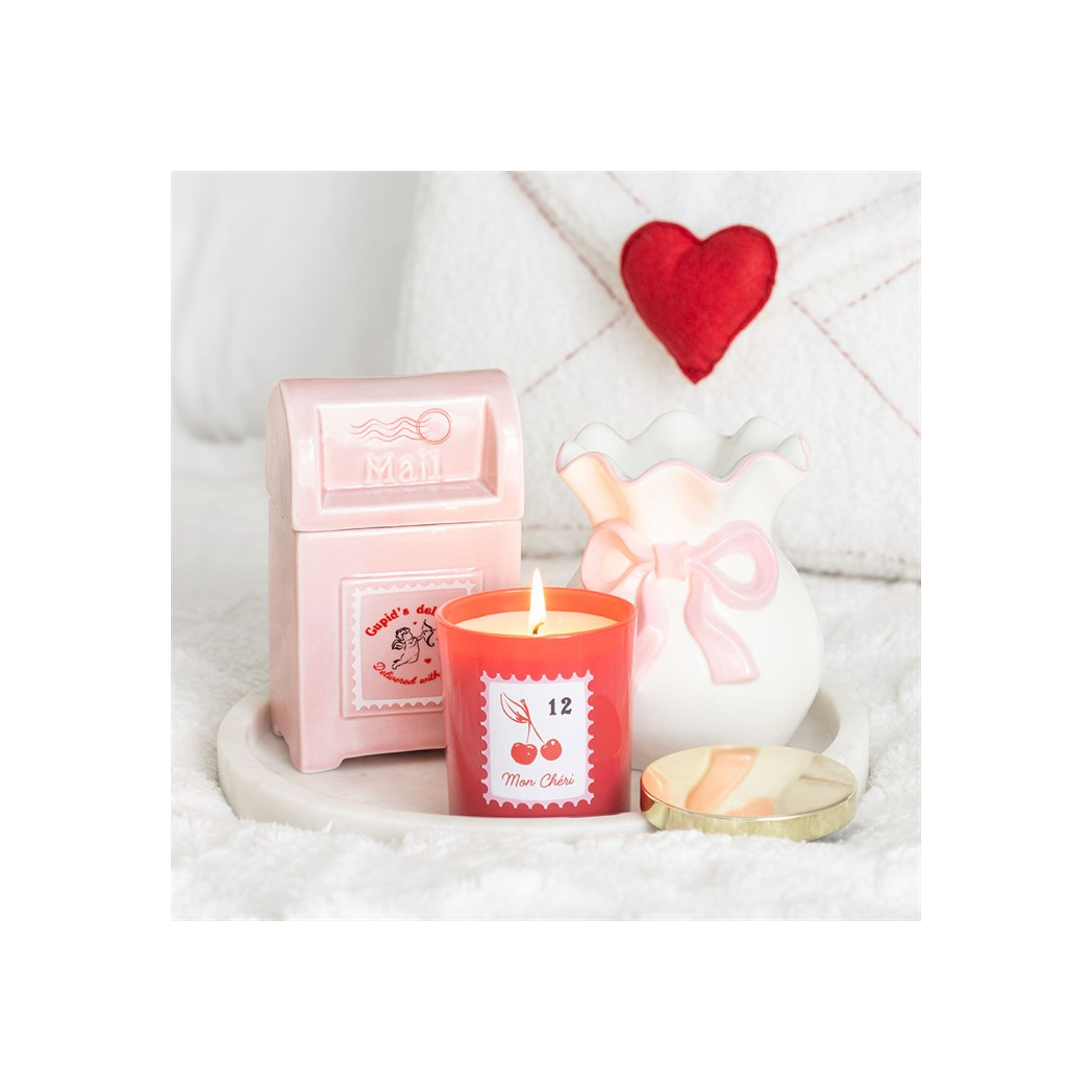 Candle with a pink packaging and heart decoration on a white background