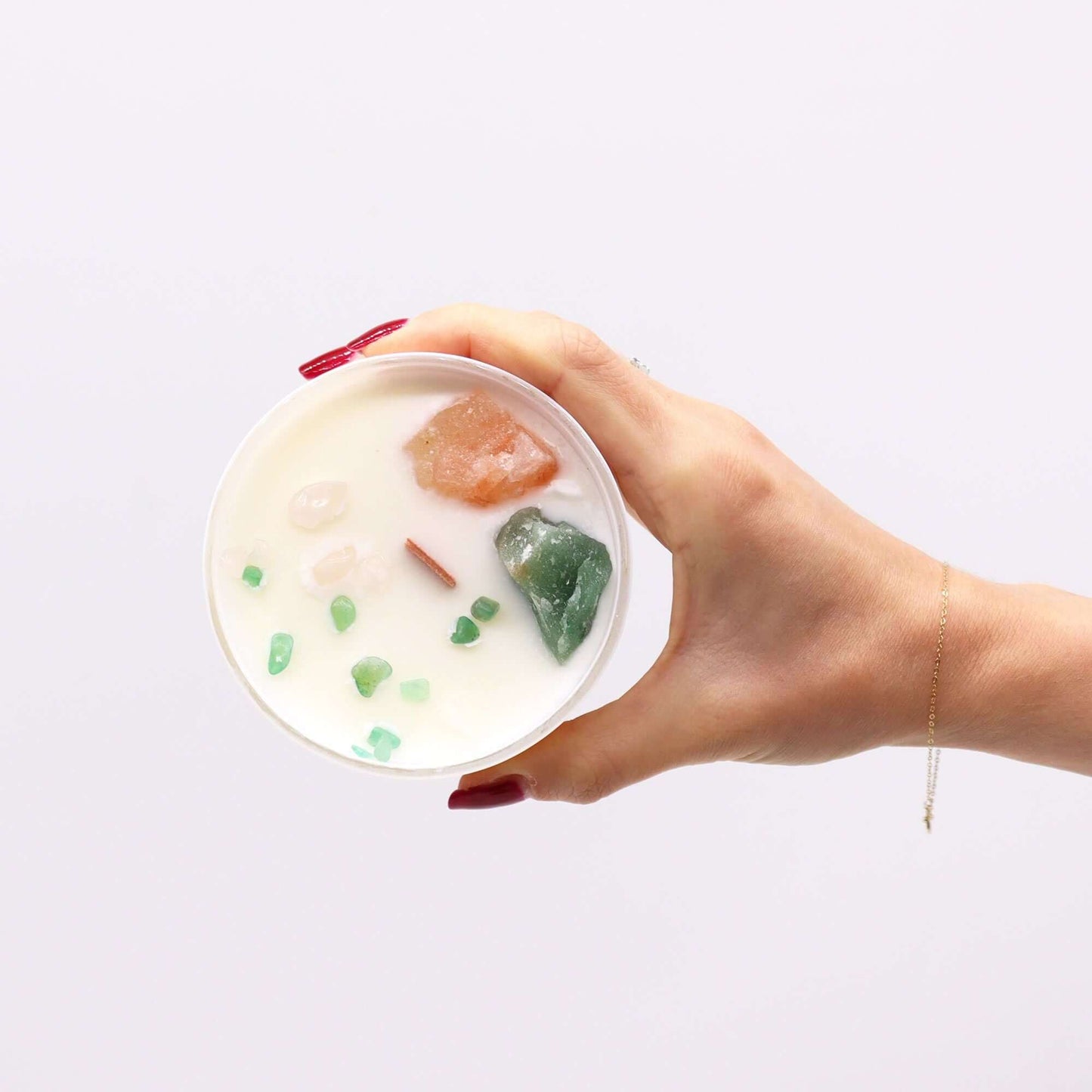 Person holding a Chakra Crystal Candle - Heart Chakra with crystals and green accents, symbolizing love and harmony.
