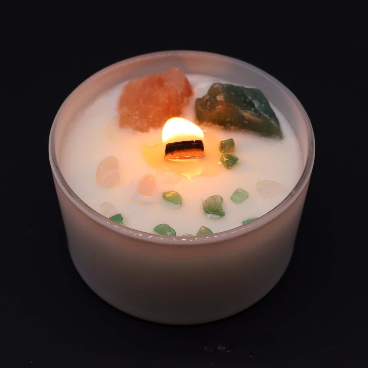 Heart Chakra candle with crystals and lit flame, promoting love and harmony.