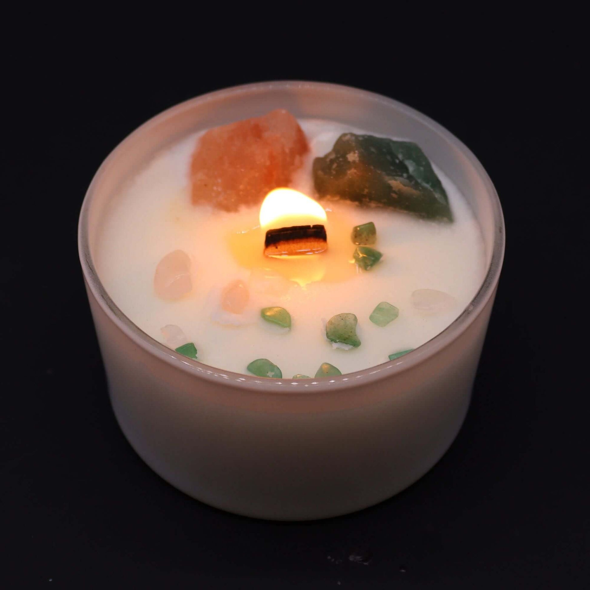 Heart Chakra candle with crystals and lit flame, promoting love and harmony.