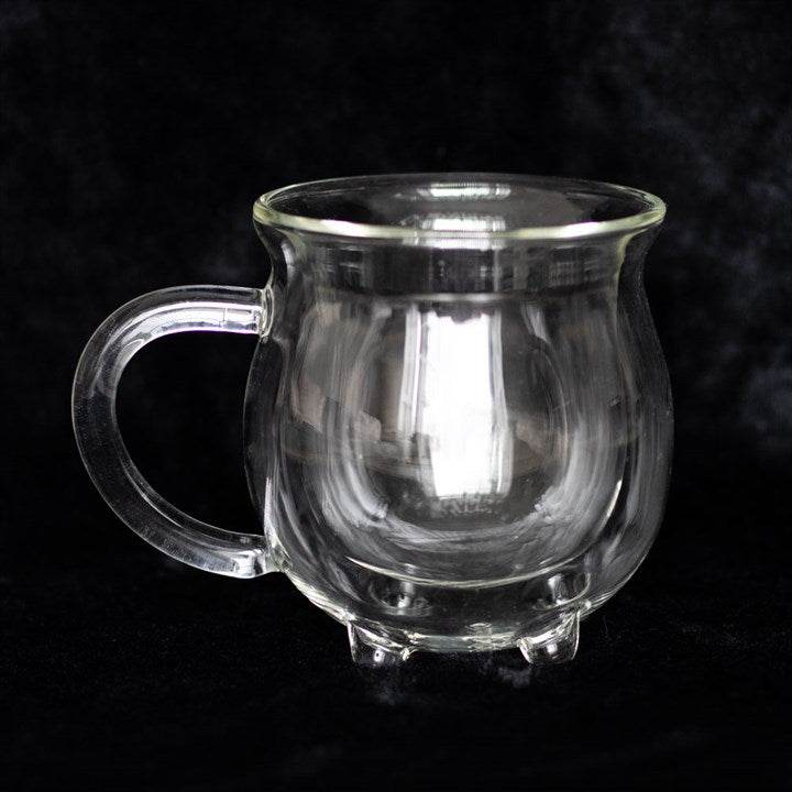Clear double walled glass cauldron mug on a dark background, perfect for magical sipping.