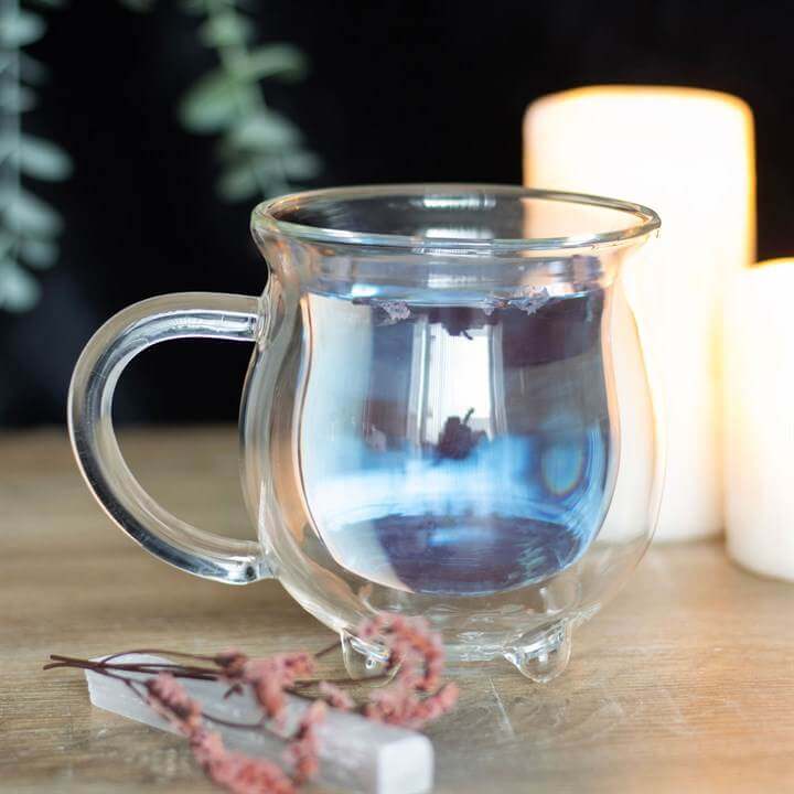 Clear double walled glass cauldron mug with flowers and candles, perfect for magical sipping.