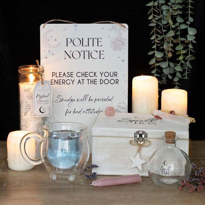 Artistic setup with a clear cauldron mug, candles, a polite notice sign, and decorative items for a magical ambiance.