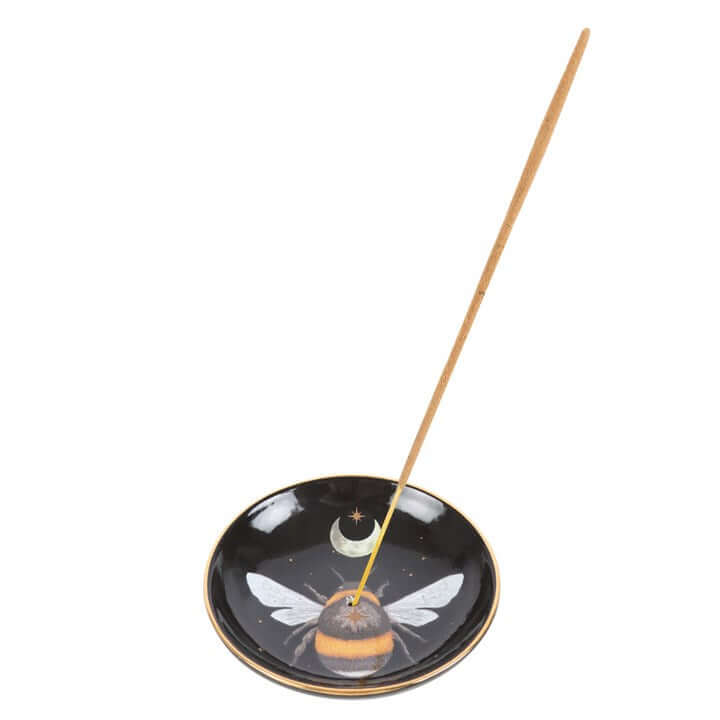 Incense stick on a black dish with a bee design on a white background