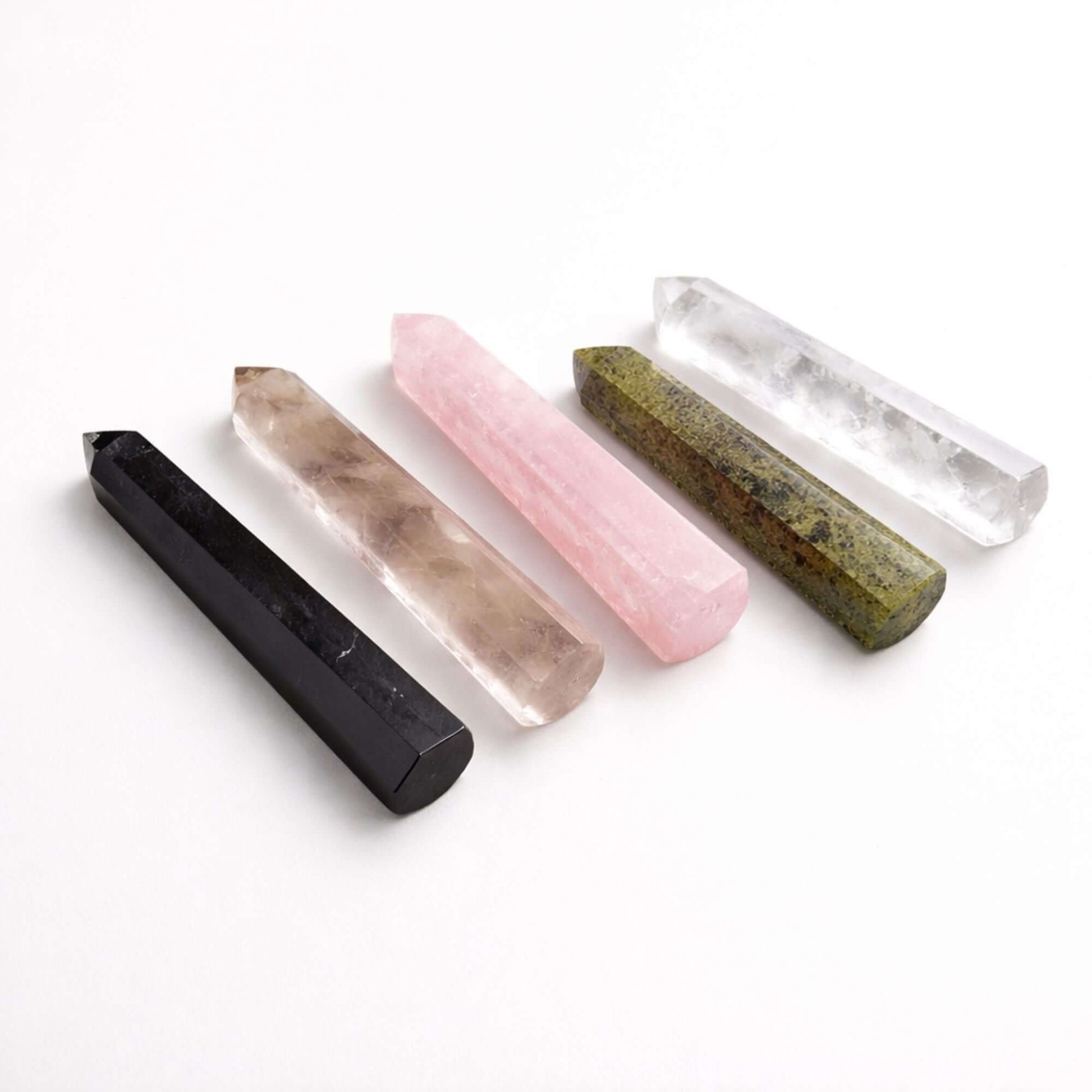 Five polished Obelisk Points in black, pink, and green showcasing unique designs and natural patterns.