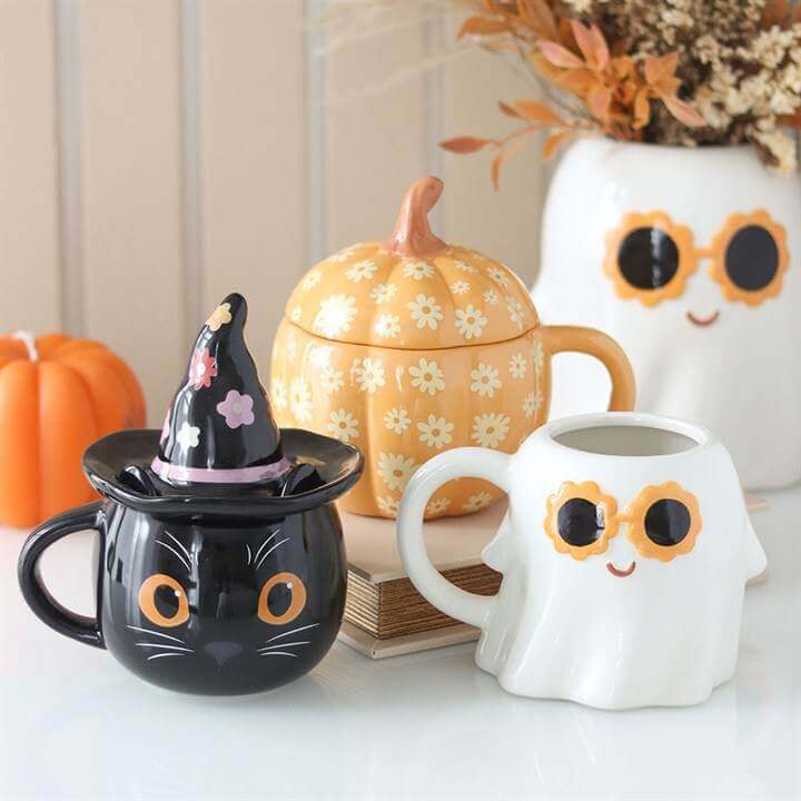 Set of whimsical ceramic mugs including a pumpkin lidded mug, Halloween cat, and ghost mugs for autumn decor.