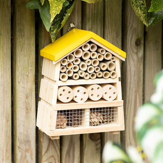 Wooden insect house for solitary bees with yellow roof, ideal for attracting wildlife to your garden.