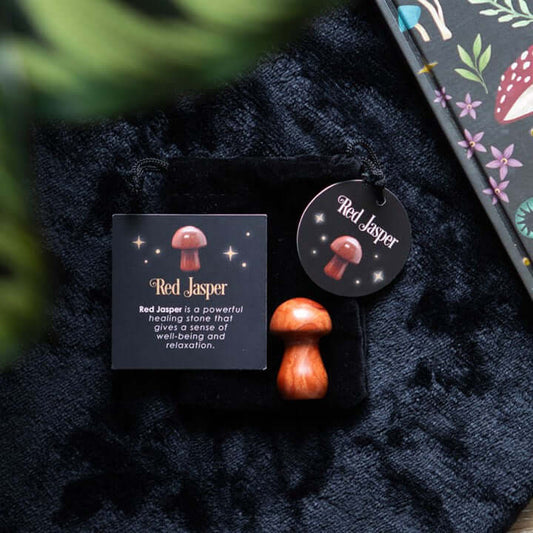 Magical Red Jasper Crystal Mushroom on a velvet surface with description card highlighting its healing properties.