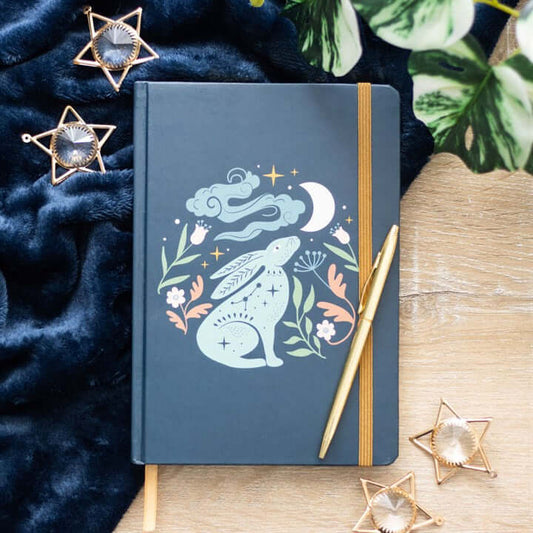 Blue notebook with a rabbit illustration on a wooden surface with decorative elements.