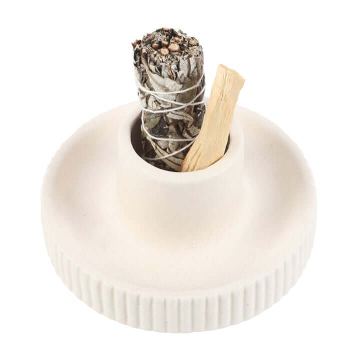 White ceramic holder with a sage bundle and wooden stick on a white background