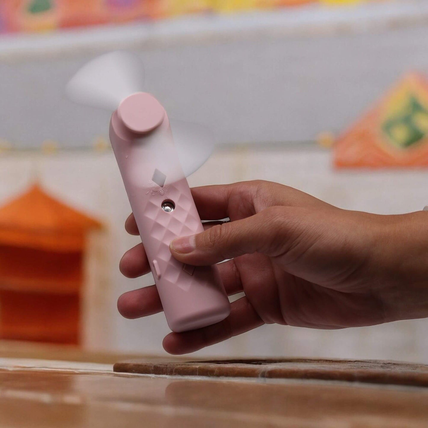 Pink Nano Mist Face Fan in a hand, featuring a compact design and mist function for on-the-go hydration.