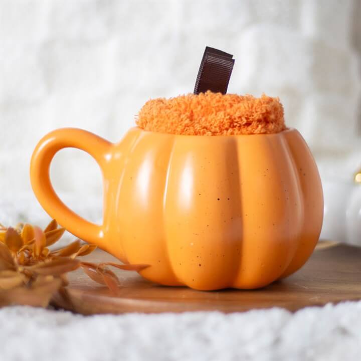 Pumpkin Shaped Mug and Socks Set with an orange pumpkin mug and fluffy orange sock, perfect for autumn lovers.