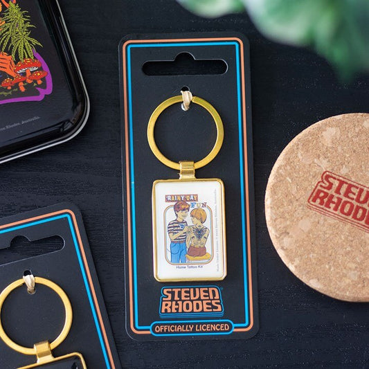 Keychain in packaging with 'Steven Rhodes' branding on a dark surface.