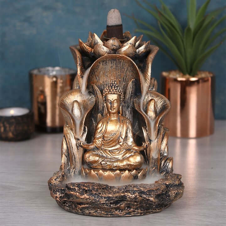 Bronze Buddha incense burner with candles and plants in the background