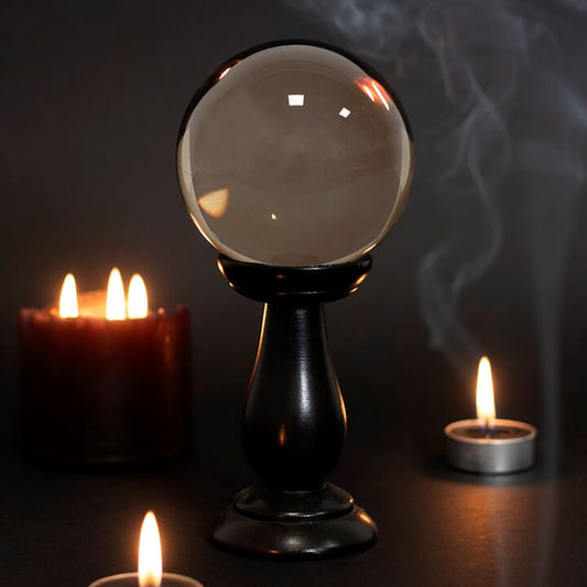 Crystal ball on a stand with candles in a dark setting