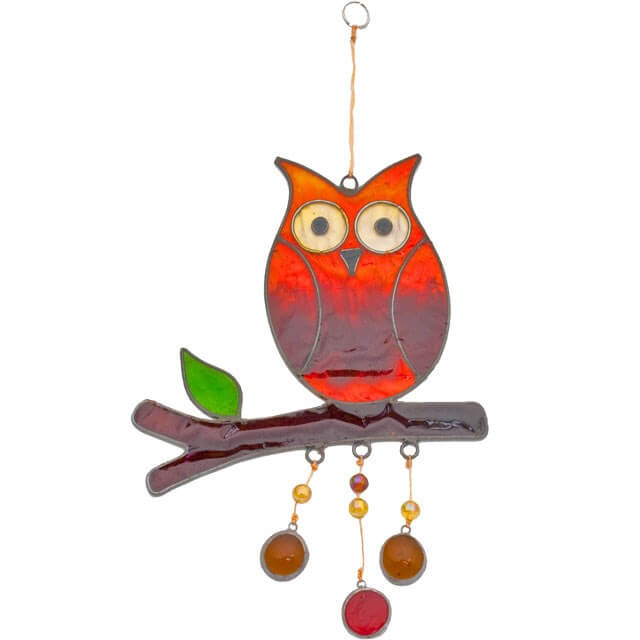 Decorative glass owl on a branch with hanging beads against a white background