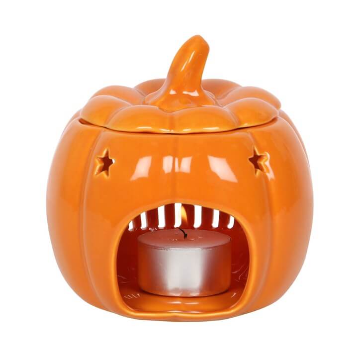 Orange ceramic pumpkin-shaped lantern with a lit candle inside on a white background