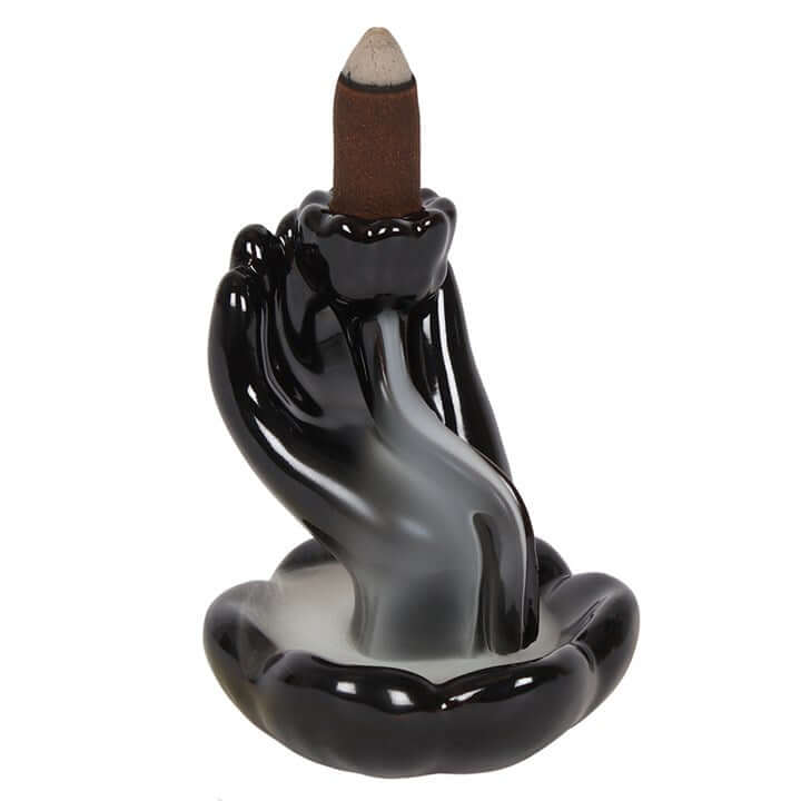Black ceramic hand-shaped incense holder with a backflow incense stick on a white background