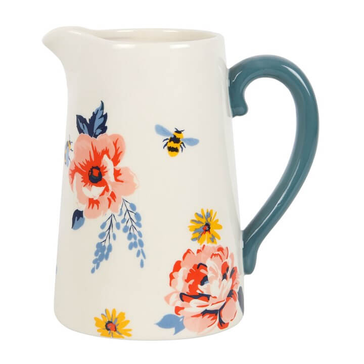 Ceramic pitcher with floral design and blue handle on a white background