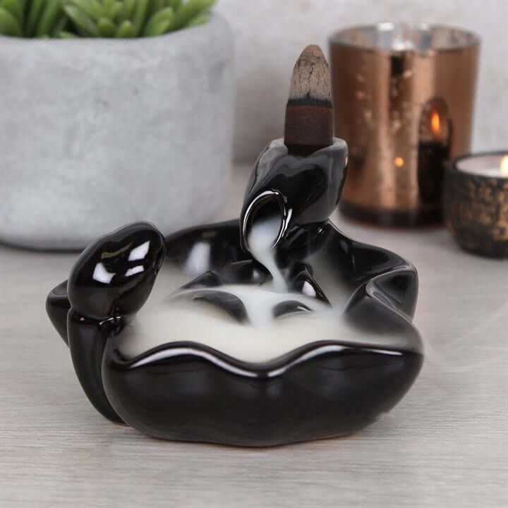 Black and white ceramic incense burner with smoke effect on a light surface.