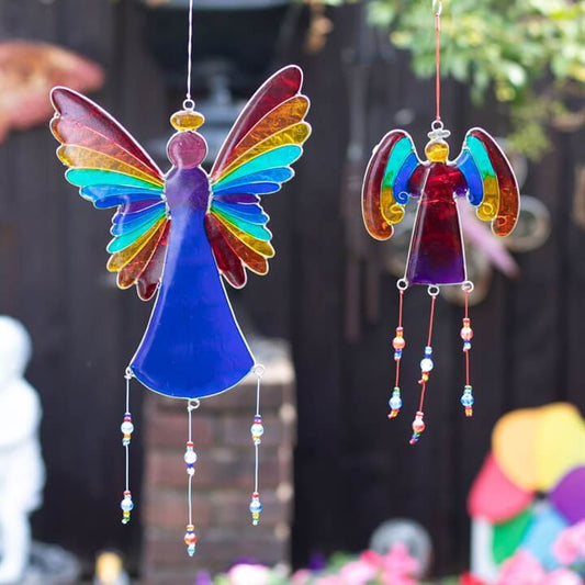 Colorful angel-shaped wind chimes with rainbow wings against a blurred outdoor background.