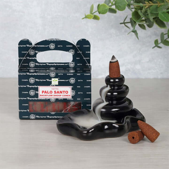 Black incense burner with Palo Santo cones on a light surface with a white background