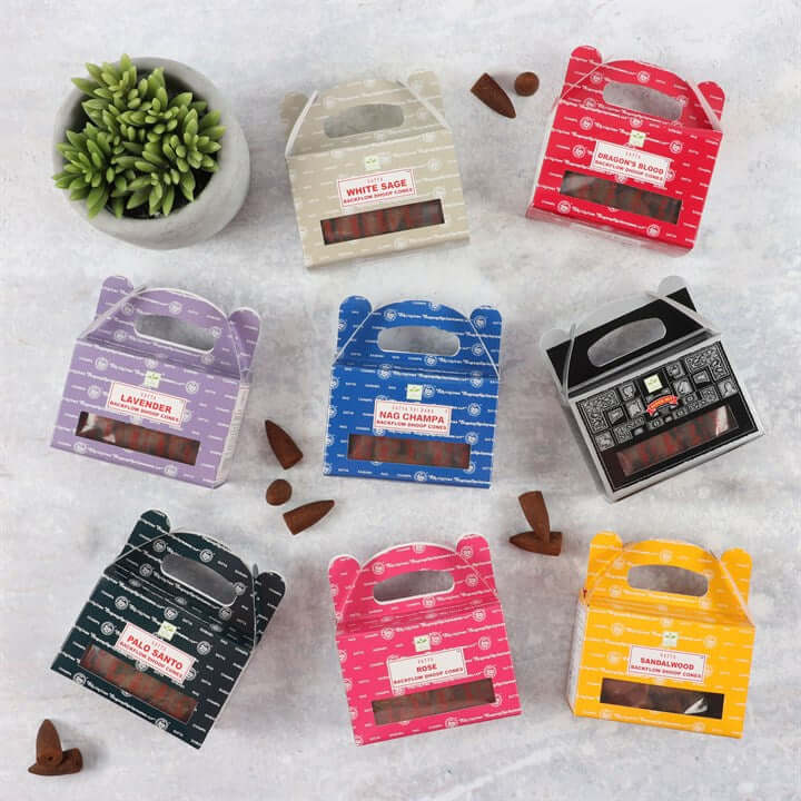 Colorful packages of incense sticks on a textured surface with a plant in the corner.