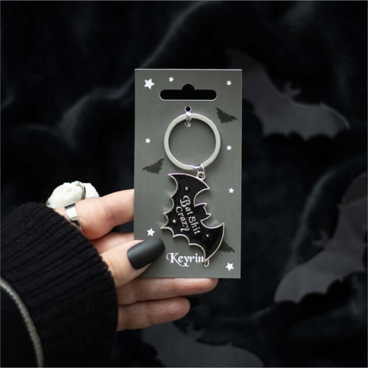 Keychain with bat design held by a hand against a dark background