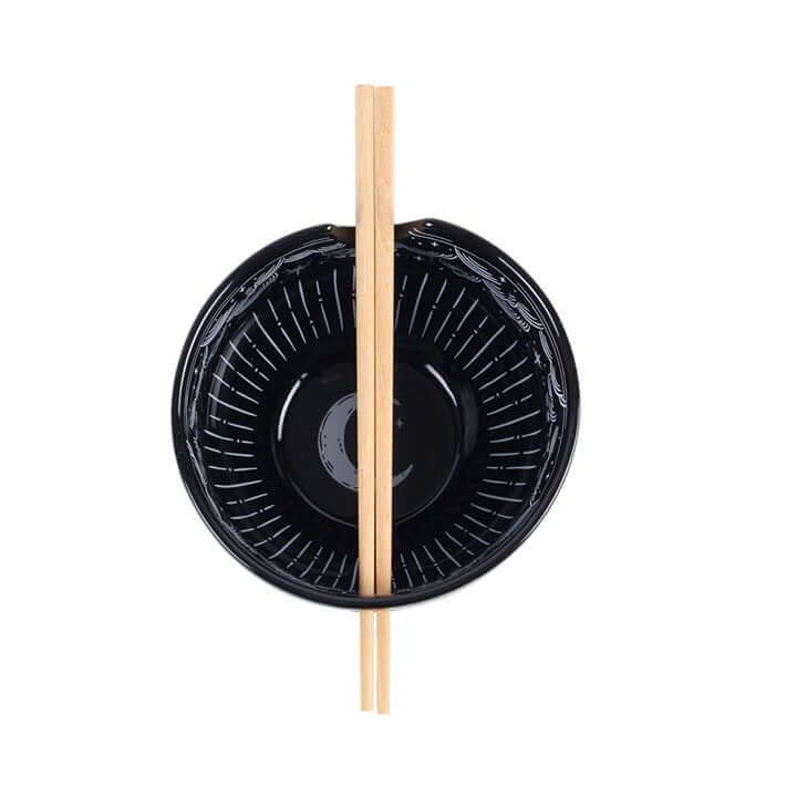 Black ceramic Spellbound Sky Noodle Bowl and Chopsticks Set with wooden chopsticks positioned in the bowl.
