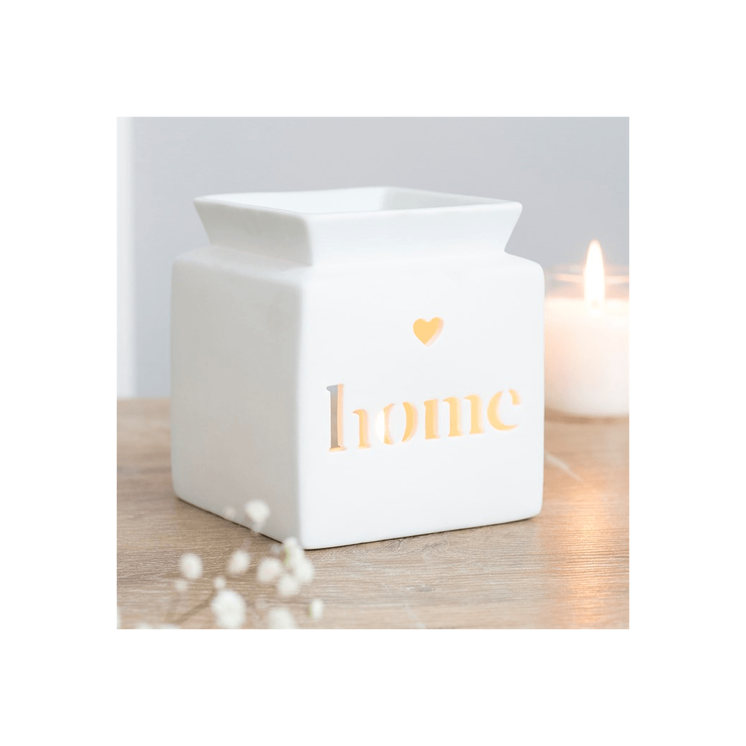 White lantern with 'home' and a heart on it, emitting a warm glow on a wooden surface.