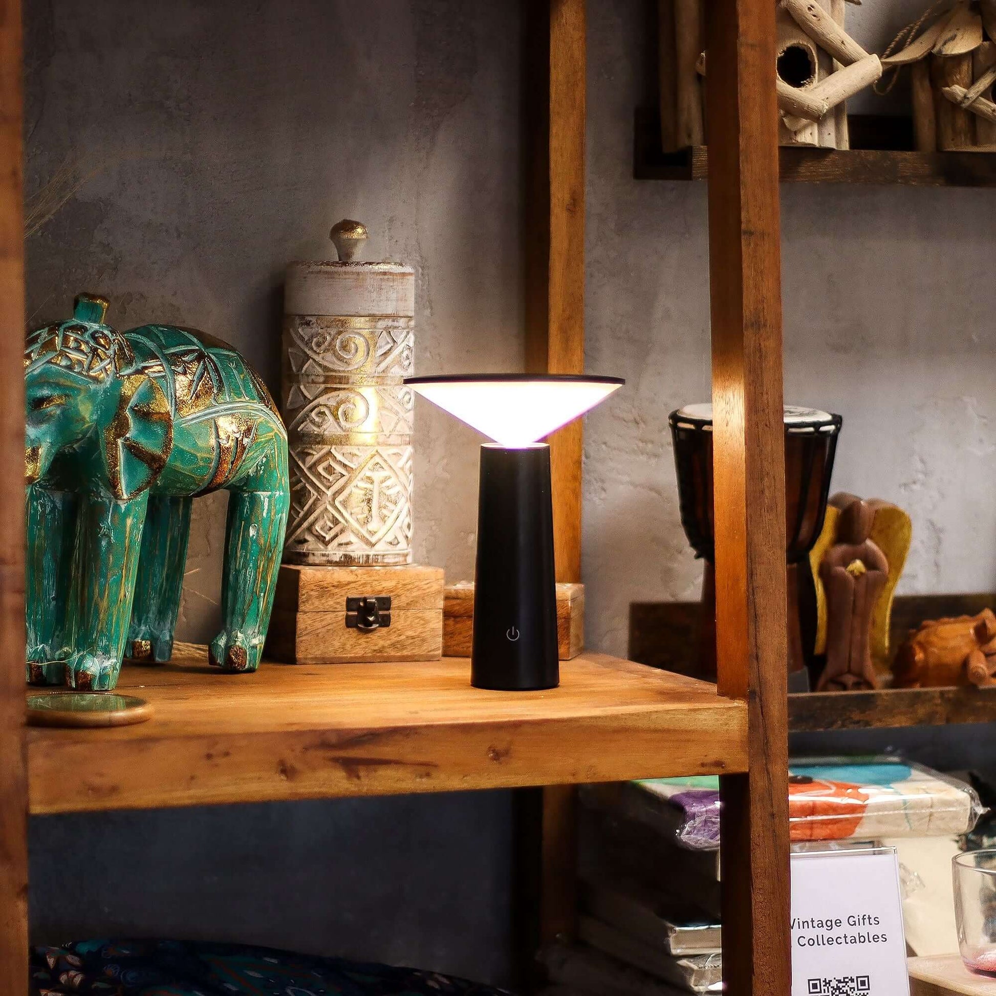 Touch Lamp with stylish design illuminating a wooden shelf filled with decorative items.