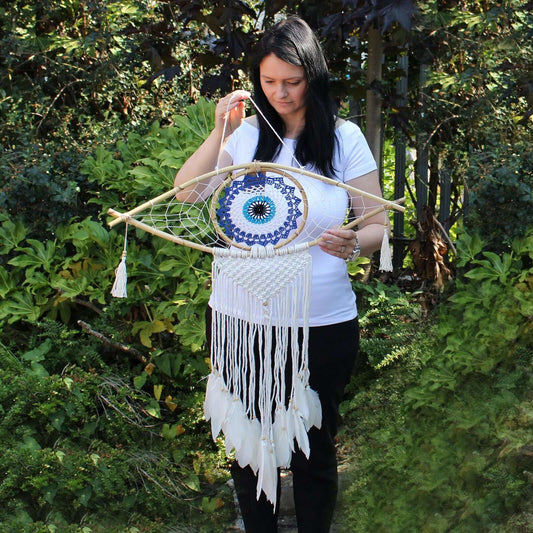 Protection Dream Catcher displayed by a woman outdoors, featuring Evil Eye in white, blue, and grey macrame design.